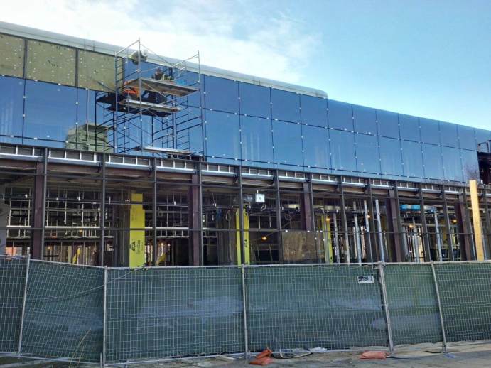 workers place glass tiles up on the new building