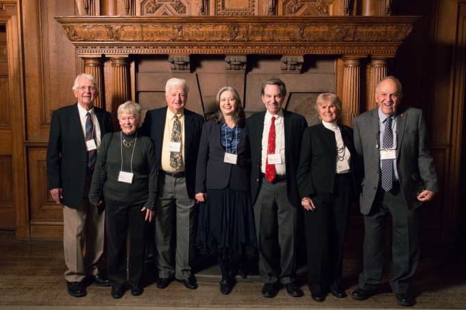 Three alumni of Class of 1955 with their spouses in front of the oak fireplace