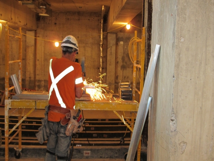 Construction worker cutting up steel remants with electric saw, sparks flying