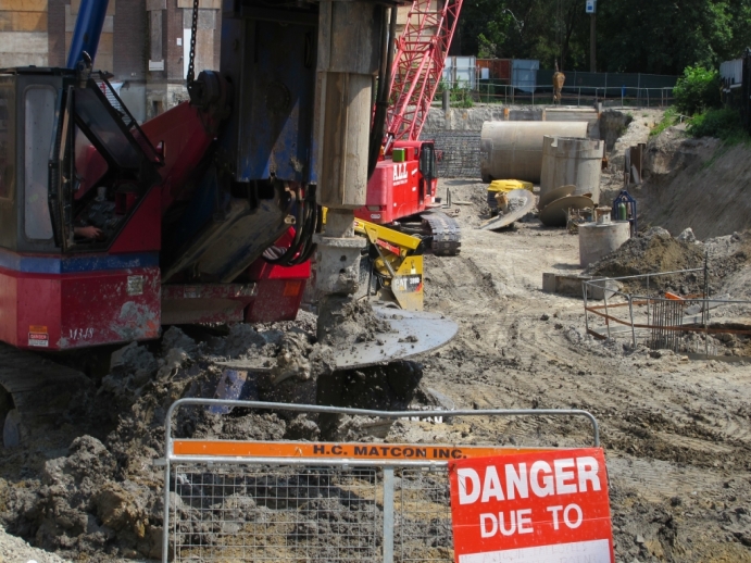 caisson driller bit shaking off mud retrieved from ground hole