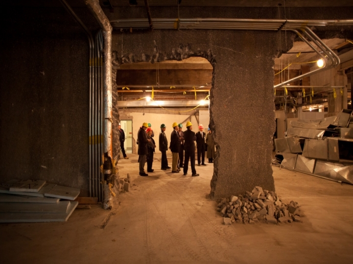 Demolition site, partial knocked out wall, people touring the site