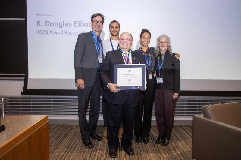 Doug holding his award, surrounded by people