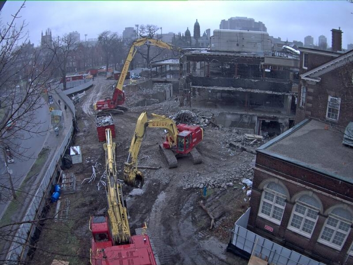 two large excavating rigs tear exterior off law library building