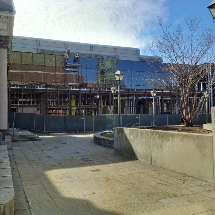 workers place glass tiles up on the new building