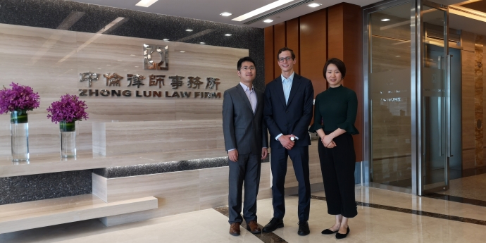 Law student D'Arcy White, centre, with colleagues from Zhong Lun Law firm, by the firm's front door in the lobby