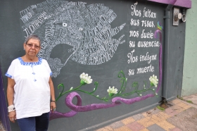 Honduran woman standing next to graffitti art in honour of dead 