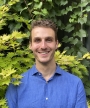 Photo of smiling man with leaves in the background